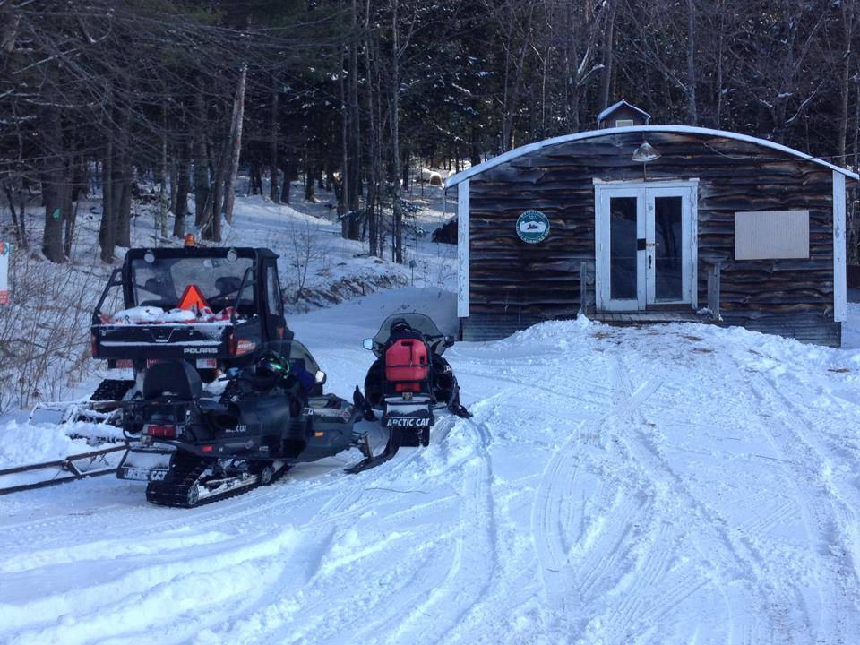 Snowmobiles and WRR equipment parked outside the clubhouse in winter.